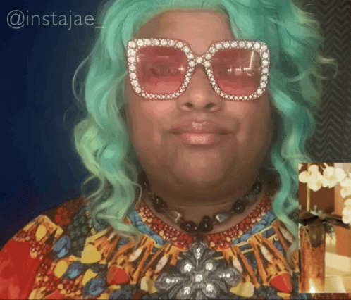 A Woman With Green Hair Wearing Sunglasses And A Necklace With The Name Instajae On The Bottom GIF