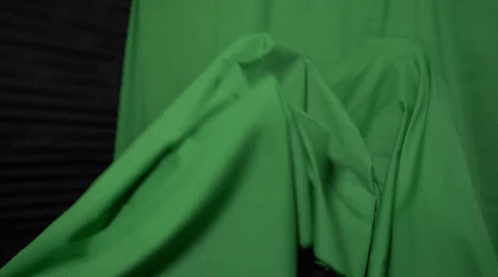 A Woman With Green Paint On Her Face Is Laying Under A Green Cloth . GIF