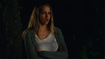 A Woman With Her Arms Crossed Is Wearing A Gray Cardigan GIF