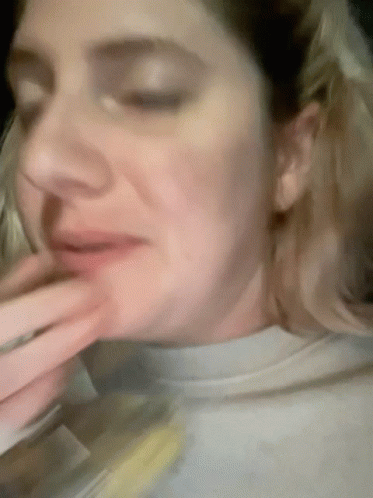 A Woman With Her Eyes Closed And Her Hand On Her Mouth GIF
