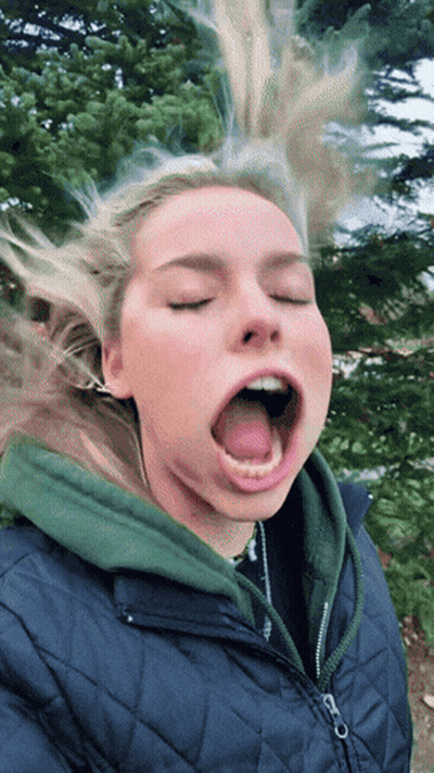 A Woman With Her Eyes Closed And Her Tongue Out GIF
