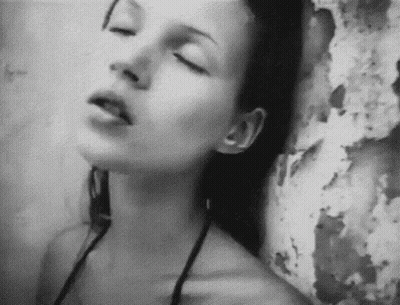 A Woman With Her Eyes Closed Is Leaning Against A Wall . GIF
