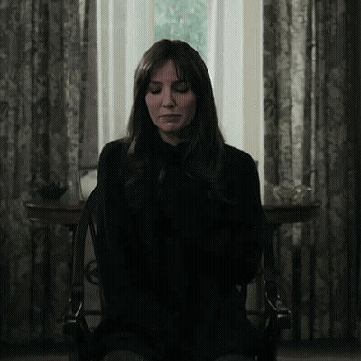 A Woman With Her Eyes Closed Is Sitting In A Chair In Front Of A Window GIF