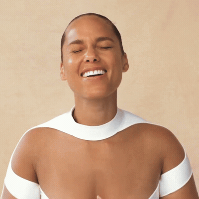A Woman With Her Eyes Closed Is Smiling And Wearing A White Top GIF