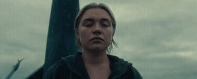 A Woman With Her Eyes Closed Is Standing In Front Of A Pole In The Dark . GIF