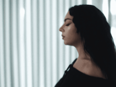 A Woman With Her Eyes Closed Is Standing In Front Of A Window GIF