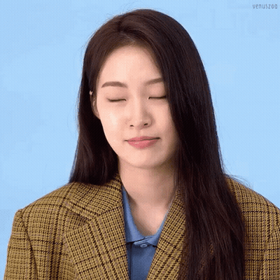 A Woman With Her Eyes Closed Is Wearing A Plaid Jacket GIF