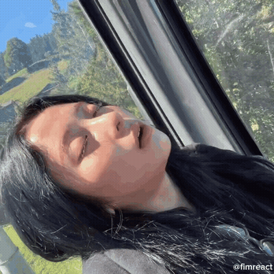A Woman With Her Eyes Closed Looks Out A Window With The Hashtag @Fimreact Below Her GIF