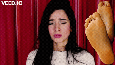 A Woman With Her Eyes Closed Next To A Pair Of Feet With The Word Veed.io On The Bottom Left GIF