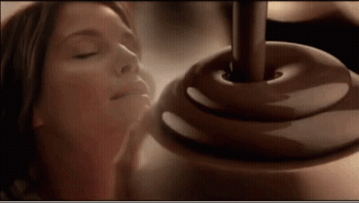 A Woman With Her Eyes Closed Smelling A Chocolate Covered Object GIF