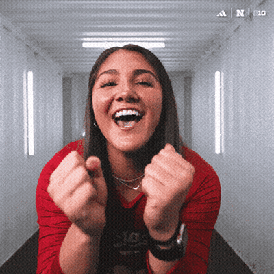 A Woman With Her Fist In The Air Is Wearing A Red Shirt That Says Adidas On It GIF