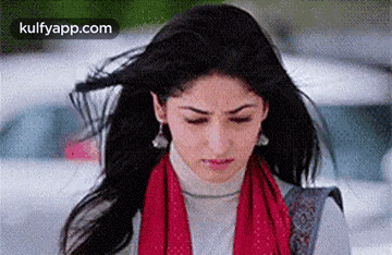 A Woman With Her Hair Blowing In The Wind Is Wearing A Red Scarf . GIF