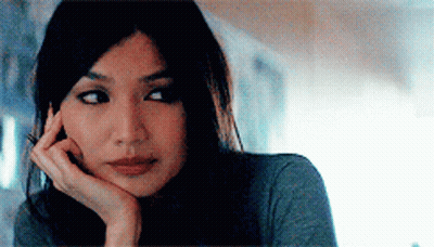 A Woman With Her Hand On Her Chin Looks At The Camera GIF