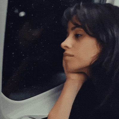 A Woman With Her Hand On Her Chin Looks Out A Window GIF