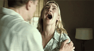 A Woman With Her Mouth Open Is Being Held By A Man In A Room . GIF