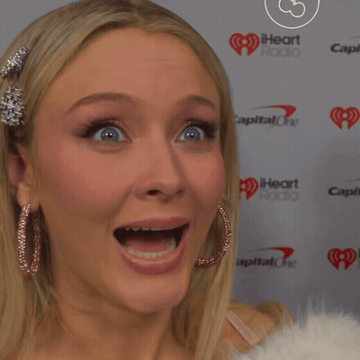 A Woman With Her Mouth Open Is Standing In Front Of A Iheart Radio Sign GIF