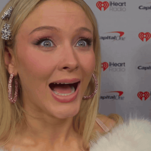 A Woman With Her Mouth Open Stands In Front Of A Wall That Says Capital One GIF