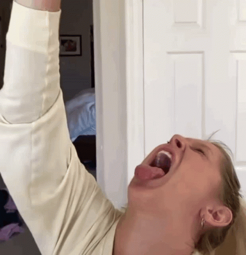 A Woman With Her Tongue Hanging Out Is Wearing A White Sweater GIF