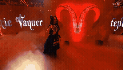 A Woman With Horns And A Trophy In Front Of A Sign That Says Ie Vaquer GIF