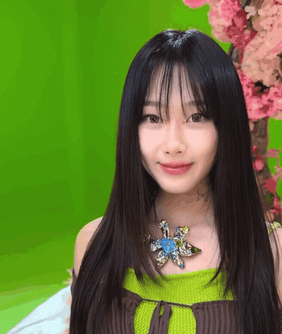 A Woman With Long Black Hair And A Flower Necklace GIF