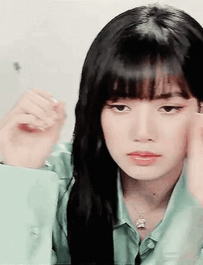 A Woman With Long Black Hair And Bangs Is Looking At Herself In The Mirror . GIF