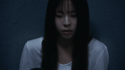 A Woman With Long Black Hair And Bangs Looks At The Camera GIF
