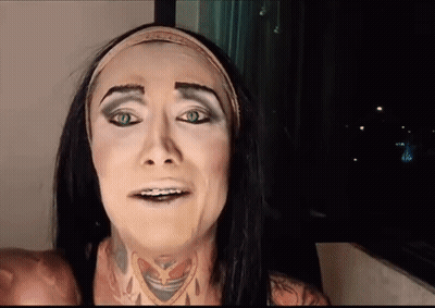 A Woman With Long Black Hair And Green Eyes Is Wearing A Headband And Making A Funny Face . GIF