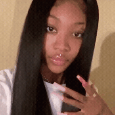 A Woman With Long Black Hair And Long Pink Nails Is Taking A Selfie . GIF