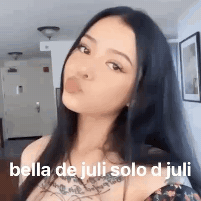 A Woman With Long Black Hair Is Blowing A Bubble With Her Mouth . GIF