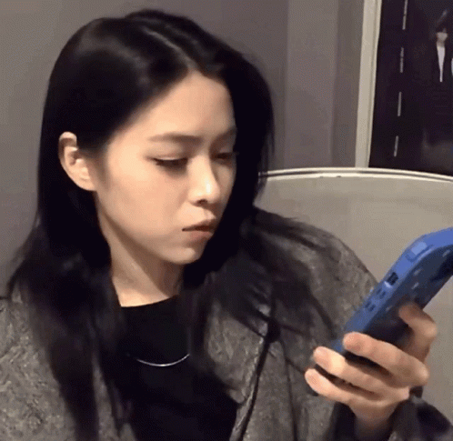 A Woman With Long Black Hair Is Holding A Blue Phone GIF