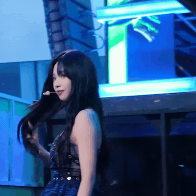 A Woman With Long Black Hair Is Holding A Microphone GIF