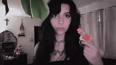 A Woman With Long Black Hair Is Holding A Small Toy Gun GIF
