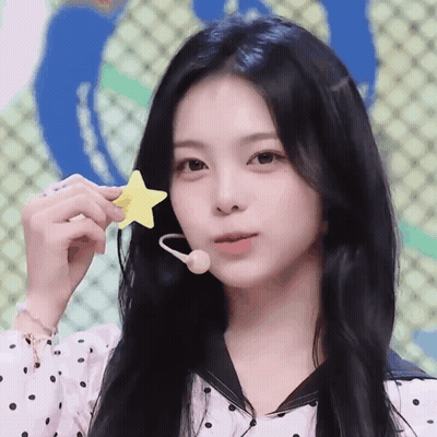 A Woman With Long Black Hair Is Holding A Yellow Star In Her Hand GIF