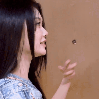 A Woman With Long Black Hair Is Looking At A Doorknob . GIF