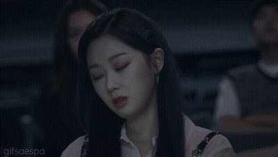 A Woman With Long Black Hair Is Sitting In A Dark Room And Looking At Something . GIF