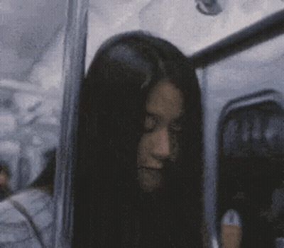 A Woman With Long Black Hair Is Sitting On A Bus And Looking At The Camera . GIF
