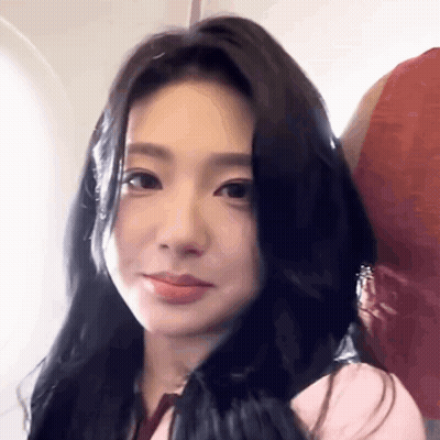 A Woman With Long Black Hair Is Sitting On An Airplane And Smiling . GIF
