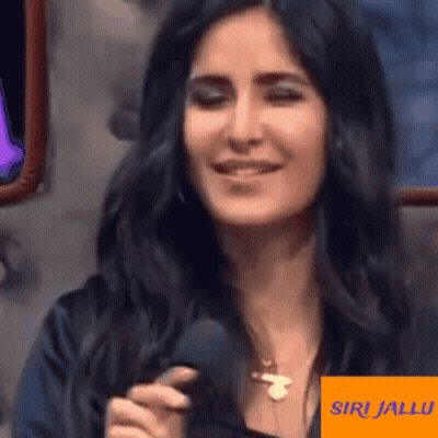 A Woman With Long Black Hair Is Smiling And Holding A Microphone GIF