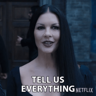 A Woman With Long Black Hair Is Smiling And Says Tell Us Everything Netflix GIF