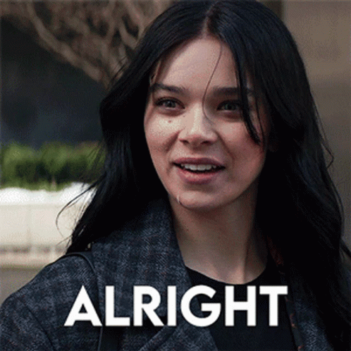 A Woman With Long Black Hair Is Smiling In Front Of The Word Alright GIF