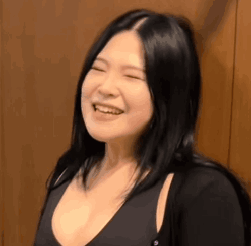 A Woman With Long Black Hair Is Smiling With Her Eyes Closed And Her Mouth Open . GIF