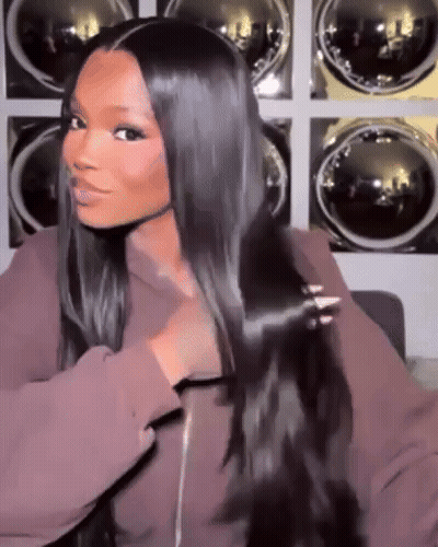 A Woman With Long Black Hair Is Standing In Front Of A Laundry Room . GIF