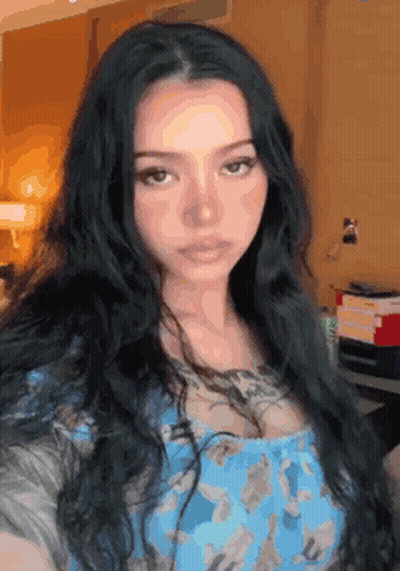 A Woman With Long Black Hair Is Taking A Selfie In A Blue Dress . GIF