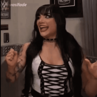 A Woman With Long Black Hair Is Wearing A Black And White Lace Up Top And Laughing . GIF