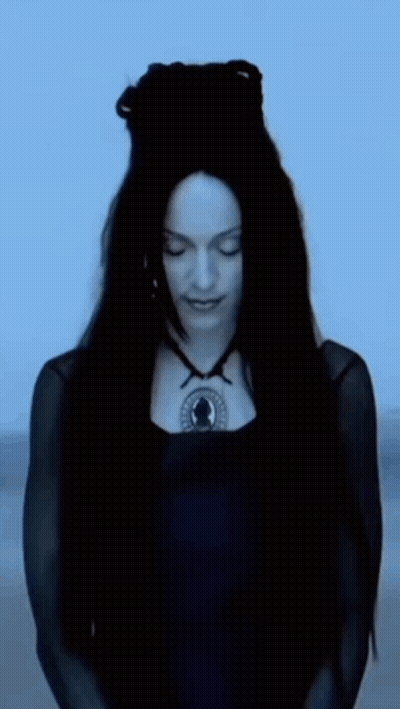A Woman With Long Black Hair Is Wearing A Black Dress And A Black Necklace GIF