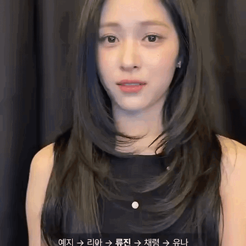 A Woman With Long Black Hair Is Wearing A Black Dress And Earrings . GIF