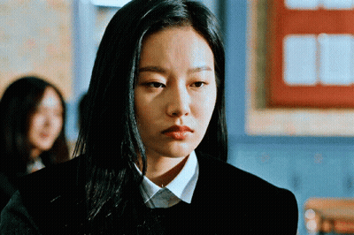 A Woman With Long Black Hair Is Wearing A Black Sweater And A White Shirt GIF