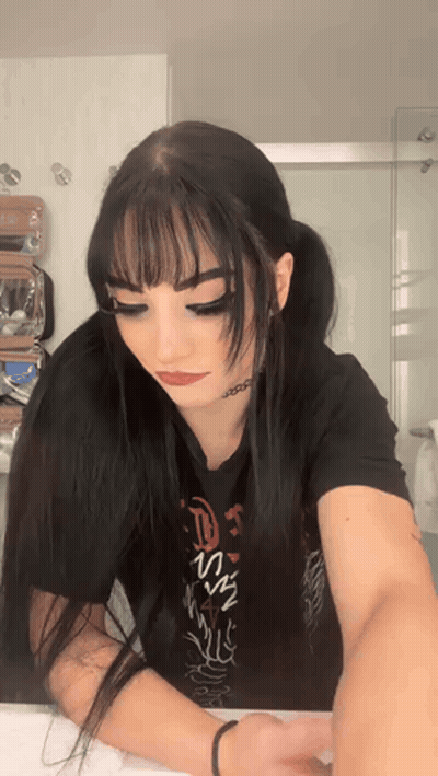 A Woman With Long Black Hair Is Wearing A Black T-Shirt With The Word Jesus On It GIF