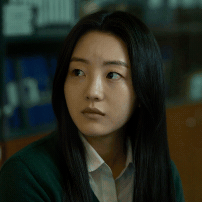 A Woman With Long Black Hair Is Wearing A Green Sweater And White Shirt GIF