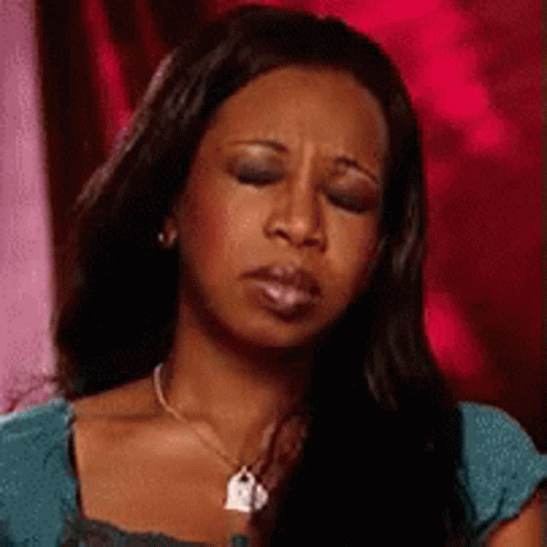 A Woman With Long Black Hair Is Wearing A Necklace And A Blue Shirt . GIF